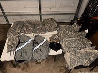 Overview of ACU jackets, trousers, PT jackets, hats and belt on table