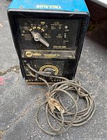 Front view showing control panel, model name, amperage dial, cable with clamp