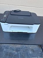 Front view showing Canon branding, white body, output tray