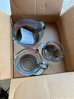 Three Pyrex glass measuring cups inside original cardboard box