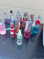 Full group of 14 assorted body mists on black tabletop