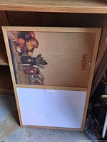 Front view of combo cork and dry-erase board showing frame, cork section with motif, whiteboard section