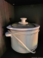 Slow cooker showing white body, clear lid, power cord wrapped around base