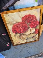 Framed canvas print with red flowers and oak-tone frame