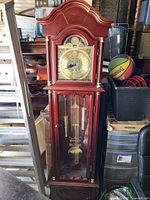 Full view of wooden grandfather clock with weights and pendulum visible through glass door