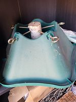 Bottom-up view of green plastic Christmas tree stand showing metal center tube and four eye-bolt screws