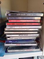 Stack of approximately 11 jewel-case music CDs showing visible titles and wear