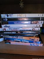 Stacked view of eleven DVD cases showing readable titles Focus, Role Models Unrated, Highwaymen, Hot Tub Time Machine Unrated, The Croods Special Edition and six partially obscured titles
