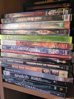 Stack of DVDs and one green Xbox 360 game case showing visible titles
