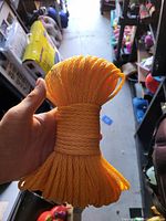 Hand holding a bundled coil of bright yellow synthetic rope