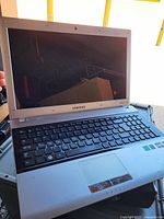 Open Samsung laptop showing screen, keyboard, AMD Vision and Windows 7 stickers