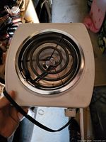 Top view of white single-burner electric hot plate with exposed coil and power cord visible