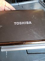 Closed laptop lid showing brown texture and Toshiba logo