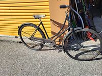 Full view of vintage black step-through cruiser bicycle leaning against storage unit door