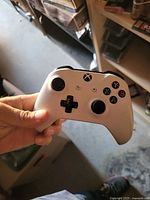 Front view of white Xbox wireless controller being held, showing buttons and overall condition