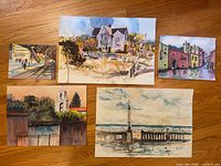 All five watercolor paintings laid out on wood floor