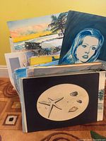 Stack of assorted unframed artworks in rack