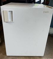 Front view of white Sanyo mini fridge, door closed, showing handle and brand badge
