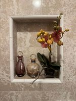 Overall view of both perfume bottles and orchid within tiled niche