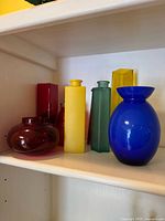 Shelf with seven multicolored glass vases