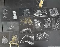 Group view of 14 scratchboard artworks arranged on table