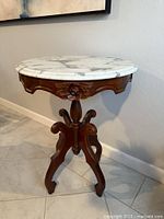 Full view of round marble top parlor table with carved wood base