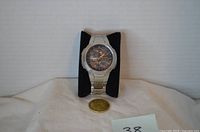 Front view of Casio Waveceptor watch on stand with coin for scale