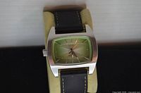 Front view showing green dial, stainless case, leather strap