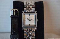 Silver-tone square watch on bracelet with adjacent leather strap