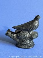 Right side view of pewter bird whistle highlighting feather detail and stump base