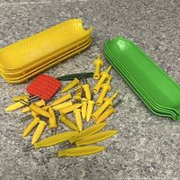 Assortment of yellow trays, green trays, corn holders, red pad on countertop