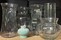 Group shot of five clear glass vases and one ceramic bud vase