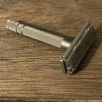 Full view of razor lying closed showing knurled handle and butterfly head