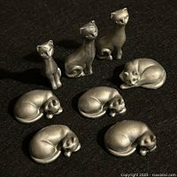 All seven pewter cat figurines on black background