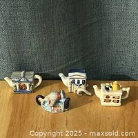 Group shot of four Wade Red Rose Tea teapot figurines on table