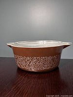 Side view of brown casserole dish with Woodland floral pattern and clear lid