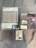 Lot overview showing three packaged items: Glacier Bay LED showerhead, Brookstone color-changing toilet paper holder, small box LED toilet bowl light