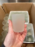 Hand holding single frosted votive holder showing size and finish
