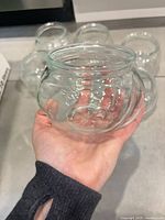 Hand holding a clear round vase showing shape and clarity