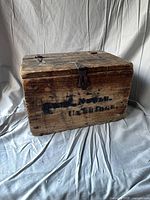 Front view of wooden box showing stencilled lettering and metal hasp
