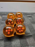 Six orange acrylic Dragon Balls with varying star counts displayed on black surface