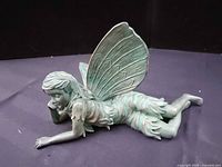 Green resin fairy figurine lying on stomach, detailed wings and dress