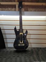 Front view of black Guitar Hero Live guitar controller showing fret buttons, strum bar and whammy bar