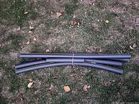 Five grey foam pipe insulation tubes bundled together on grass