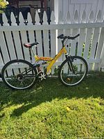 Full view of yellow Tim Hortons mountain bicycle against fence