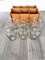 Six clear glass pitchers with cardboard divider