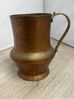 Full view of pitcher showing copper body and brass handle