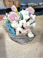 Front view showing fish figures, coral branches and seashell on rock base