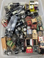 Plastic bin filled with loose and boxed vacuum tubes, various brands visible