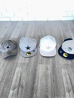 All four Dallas Cowboys caps lined up on floor